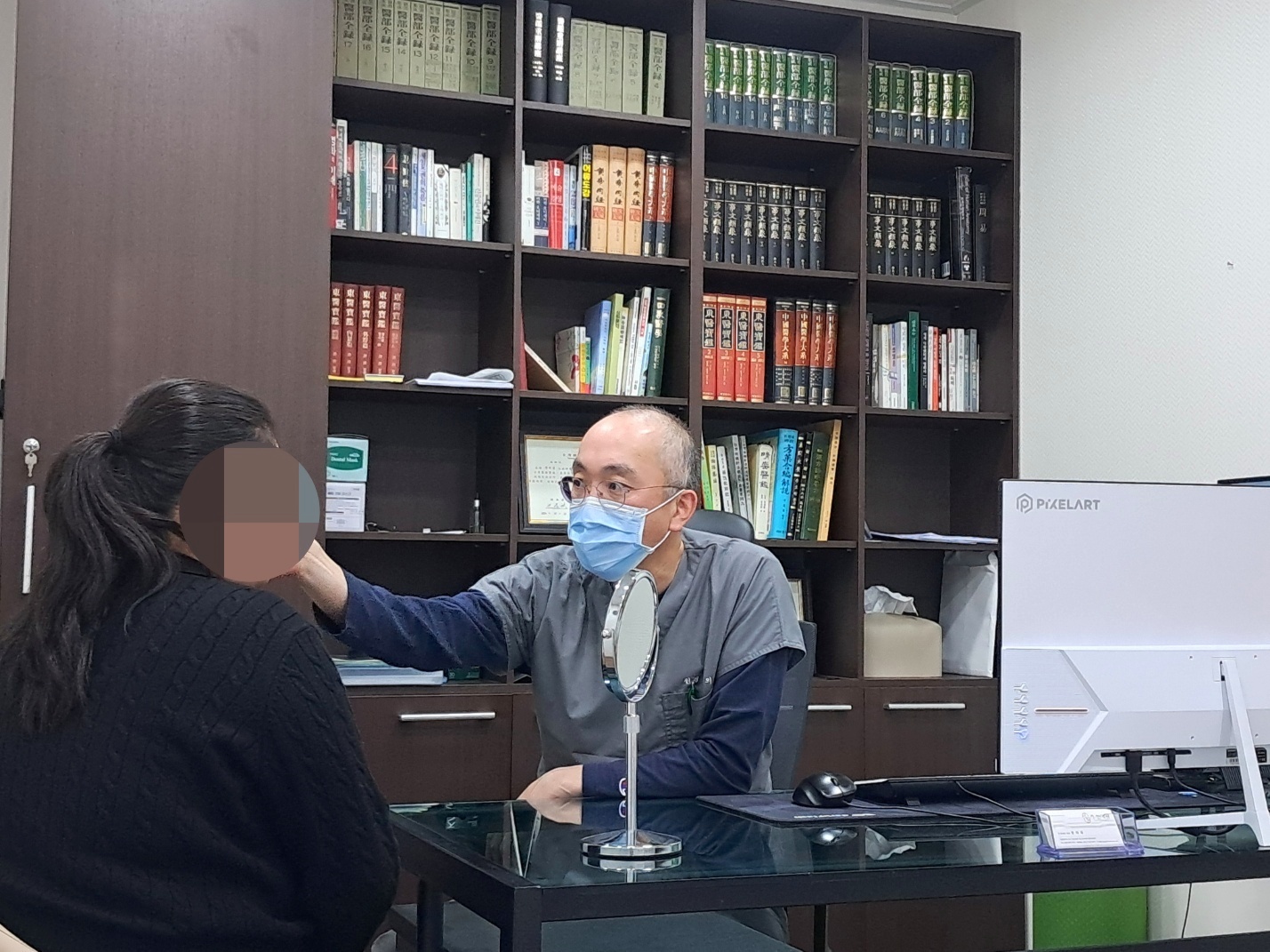 원장이 환자의 얼굴을 살피며 거울로 설명하는 진료실 상담
